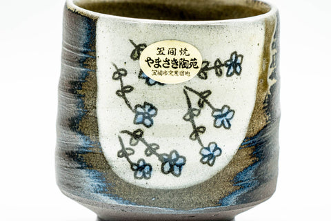 Close-up of one white cup featuring the painted floral motif and calligraphic characters.