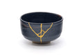 Front view of the jet-black chawan with a gold kintsugi repair line.