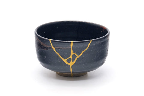 Front view of the jet-black chawan with a gold kintsugi repair line.