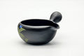 Three-quarter view of the black clay yuzamashi showing the side handle and painted leaves.