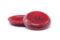 Pair of red spiral-grained wooden chataku saucers overlapping, viewed from a low angle