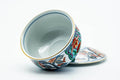 The cup tipped with the lid removed, revealing the white glazed interior.