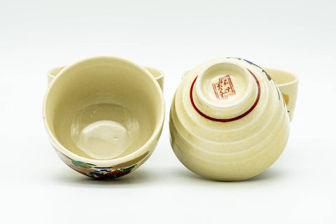 Two of the beige Kutani-yaki teacups, one upright showing the plain cream interior and one inverted to reveal the unglazed foot and red maker's seal.