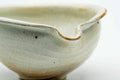 Three-quarter view highlighting the spout and the ash-toned markings on the beige glaze.