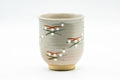 Front view of the cup showing the cream glaze and the delicate hand-painted sprig pattern.