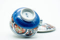 The cup tipped to show its footed base, lid resting alongside.
