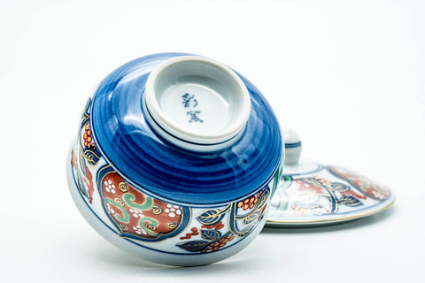The cup tipped to show its footed base, lid resting alongside.