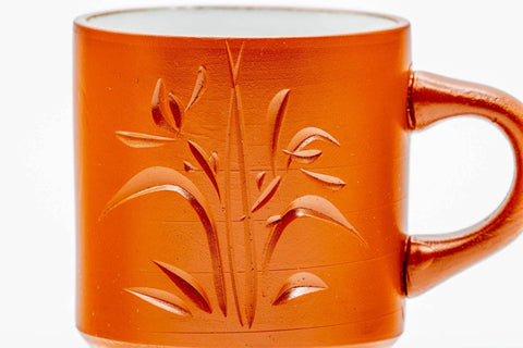 Close-up of the engraved bamboo design on the red clay body, handle visible.