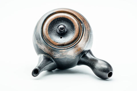 Overhead view of the domed lid and knob, with brown drip glaze radiating over the matte black surface.