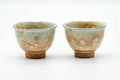 Front view of the pair of teacups showing their footed forms and warm spotted glaze.