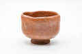 Front view of the rustic raku chawan showing the soft pink-orange surface.