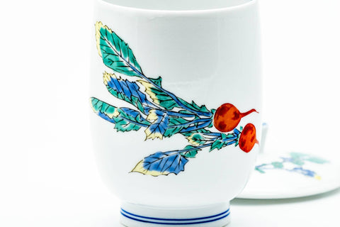 Close-up of the painted turnip with red roots and green leaves on the white porcelain.