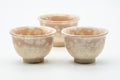 Set of three Hagi-yaki yunomi with pink gohonte blush over a pale glaze, grouped together.