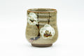 Beige speckled plum-blossom yunomi teacup, front view showing the cream glaze with painted plum-blossom motif and horizontal throwing rings.