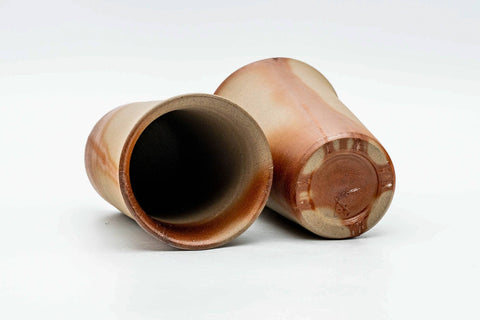 One cup tipped on its side to show the foot, beside the upright second cup.