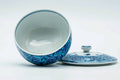 The cup tilted with the lid beside it, showing the white glazed interior.