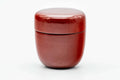 Front view of the closed red lacquer caddy with its rounded body and domed lid.