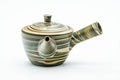 Three-quarter front view of a weathered green-and-brown marbled nerikomi Tokoname-yaki kyusu, lid on, side handle right and spout left.