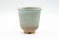 Front view of the Hagi teacup showing the blue glaze drip against the milky pale surface.