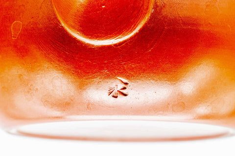 Closeup of the glossy red shudei body and base of the Tokoname kyusu with a small maker's stamp