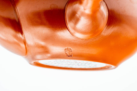 Close-up of the lower body and base resting on a white surface, highlighting the smooth red shudei clay.