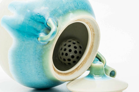 Overhead closeup looking into the Agano-yaki teapot's mouth, showing the perforated ceramic strainer and turquoise glaze
