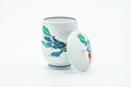 White porcelain Arita-yaki lidded yunomi painted with a turnip motif, shown with the lid set beside it.