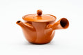Side profile of the red clay teapot, spout to the left and hollow side handle facing the viewer.