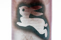 Close-up of the white leaping rabbit design on the cup's surface.