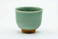 Turquoise celadon teacup with a snowflake crackle glaze and a gold-painted foot, front view.