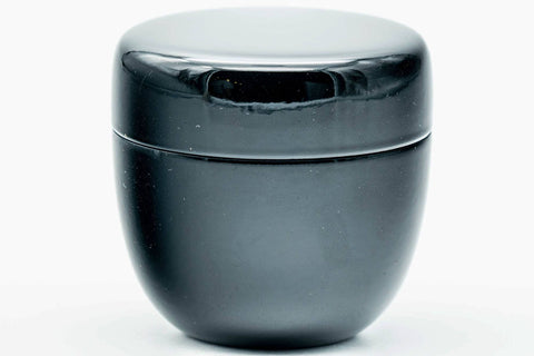 Close front view of the glossy black lacquer natsume caddy with the lid on.