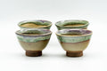 Set of four small Agano-yaki guinomi sake cups with beige-to-green drip glaze, clustered together on a white background.