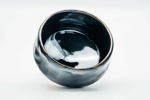 Overhead view looking into the glossy black interior of the chawan