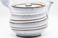 Close-up of the spiraling ribbed bands in the milky-white glaze with brown-toned edges.