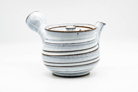 Side view of the teapot, lid on, emphasising the spiraling ribbed texture of the milky-white glaze.