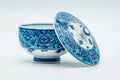 Blue-and-white Arita-yaki lidded yunomi teacup with its lid removed, cup and lid side by side showing dense blue floral patterning.