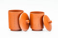 The two lidded cups with lids lifted off and leaning against them, showing the engraved calligraphy on the bodies.