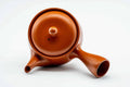 Overhead view of the round red kyusu, lid on, showing the handle and spout.