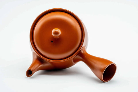 Overhead view of the round red kyusu, lid on, showing the handle and spout.