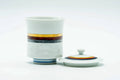 The cup upright with its lid lying flat beside it, showing the top of the lid.