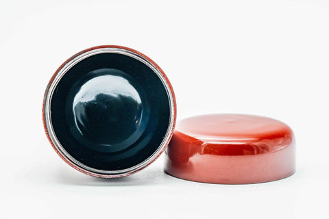 The red caddy open and upright, looking into the dark glossy interior, with the red lid lying flat beside it.