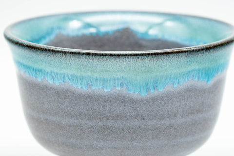 Close-up of a single Agano-yaki yunomi showing the turquoise drip-glaze detail