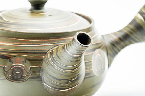 Angled view highlighting the carved circular medallions and the spiral end of the side handle.