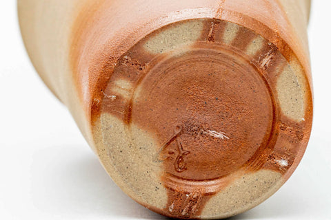 Angled close-up showing the unglazed clay bases and feet of the two cups.