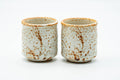 The two yunomi teacups side by side, front view, showing the shino glaze and brushwork.