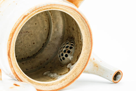 Teapot with the lid removed, angled to reveal the interior and built-in ceramic strainer.