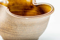 Close-up of the wavy rim with amber glaze pooling against the pale ash exterior.