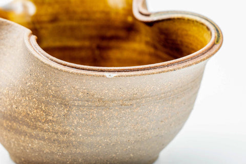 Close-up of the wavy rim with amber glaze pooling against the pale ash exterior.