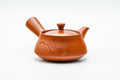 Three-quarter view of the red clay teapot, lid on and side handle to the right.