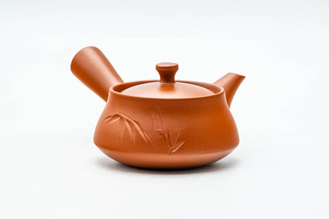 Three-quarter view of the red clay teapot, lid on and side handle to the right.
